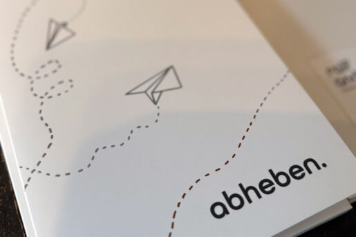 Detailansicht der Direct-Mailing-Soundkarte mit Papierflieger und Schriftzug ‚abheben‘.