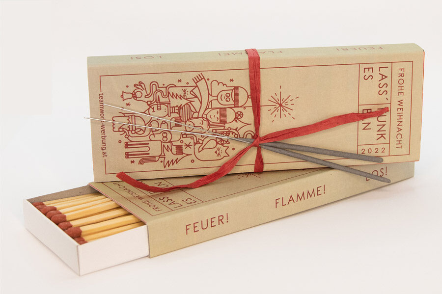 Weihnachtsmailing in Form einer übergroßen Streichholzschachtel mit der Aufschrift ‚Frohe Weihnacht – lass Funken fliegen‘, inklusive Wunderkerzen.