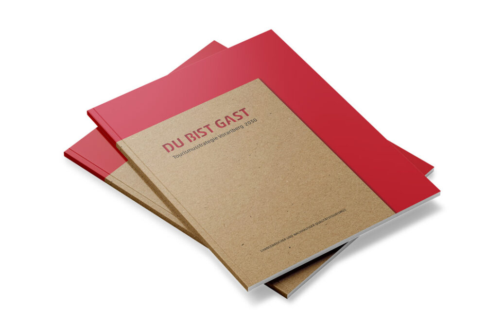 Titelblatt der Tourismusstrategie Vorarlberg 2030 mit rotem Einband und naturfarbenem Umschlag, Aufschrift „Du bist Gast“.